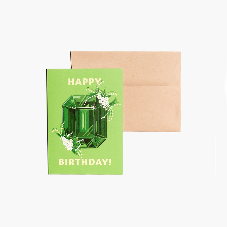 Happy Birthday card showcasing an illustrated May birthstone of emerald and birth flowers of lily of the valley.