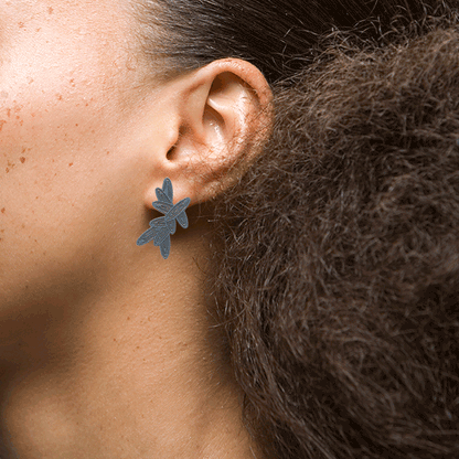 Flat stud earrings by Sorrel Van Allen featuring a finely pierced pattern of overlapping petals. Feather-light design for comfortable, all-day wear. Made from powder-coated brass with sterling silver ear posts and earring backs.