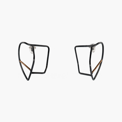 A pair of earrings featuring a fine irregular line that twists and turns, creating a unique take on a hoop earring. The earrings are made of blackened sterling silver and accented with 14k gold, adding a striking contrast to the design. The earrings exude a modern elegance and contemporary flair, perfect for adding sophistication to any outfit.