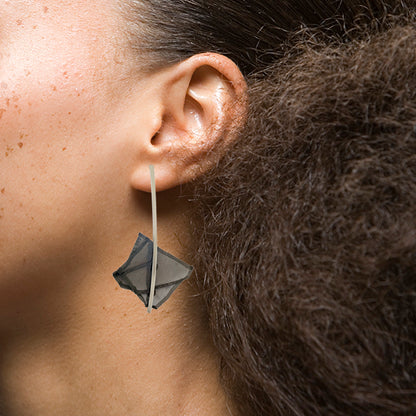 Sterling silver earrings with folded steel mesh design, hanging gracefully on an ear - Trajectory Earrings.