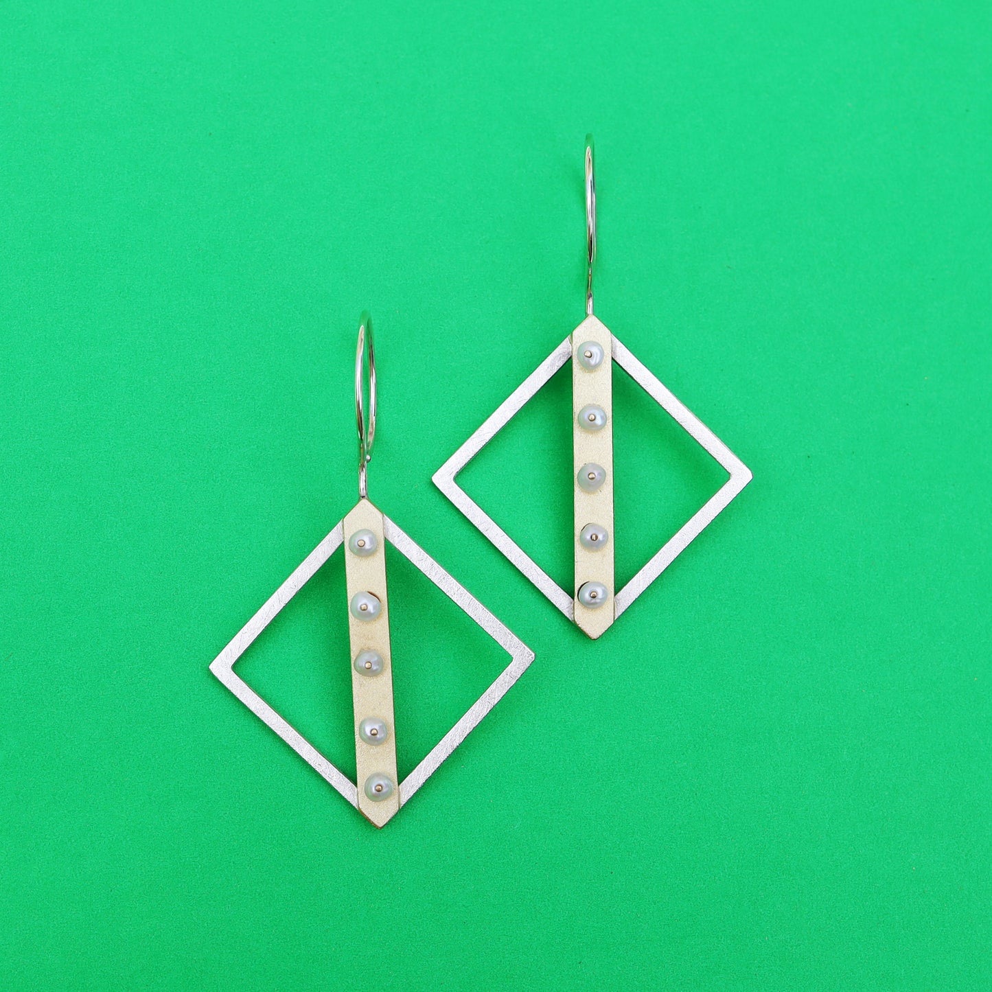 Sterling silver diamond-shaped earrings with gold line and pearl accents.