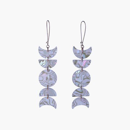 Front view image of Indi City Moonphase Earrings in abalone-patterned acrylic. These long drop earrings beautifully capture a fusion of cultural and contemporary styles, symbolizing the ever-changing phases of the moon.