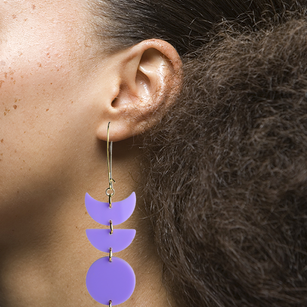 Model view image of Indi City Moonphase Earrings in purple acrylic. These long drop earrings beautifully capture a fusion of cultural and contemporary styles, symbolizing the ever-changing phases of the moon.