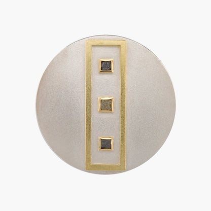 Front view image of Janis Kerman's versatile brooch and pendant. Crafted from sterling silver and 18k yellow gold, it features a unique design with a line of three square diamonds, expertly balancing geometric precision and organic beauty.