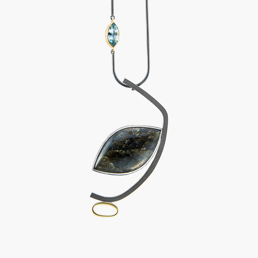 Closeup image of the pendant on Janis Kerman's one-of-a-kind sterling silver statement necklace with labradorite and blue topaz accents, expertly crafted to emphasize balance and asymmetry. Suspended from a snake chain, adorned with 18k gold detailing, and masterfully made in Quebec.