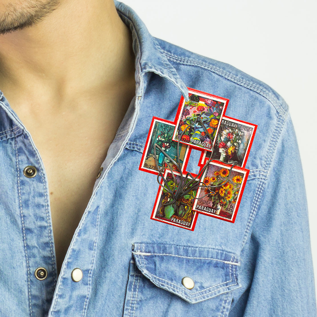 A red brooch featuring colorful postage stamps from Paraguay arranged in a mosaic-like pattern depicting various paintings of flowers by French artist Paul Cézanne. The brooch challenges traditional jewelry values and highlights social and political themes of currency and material use.